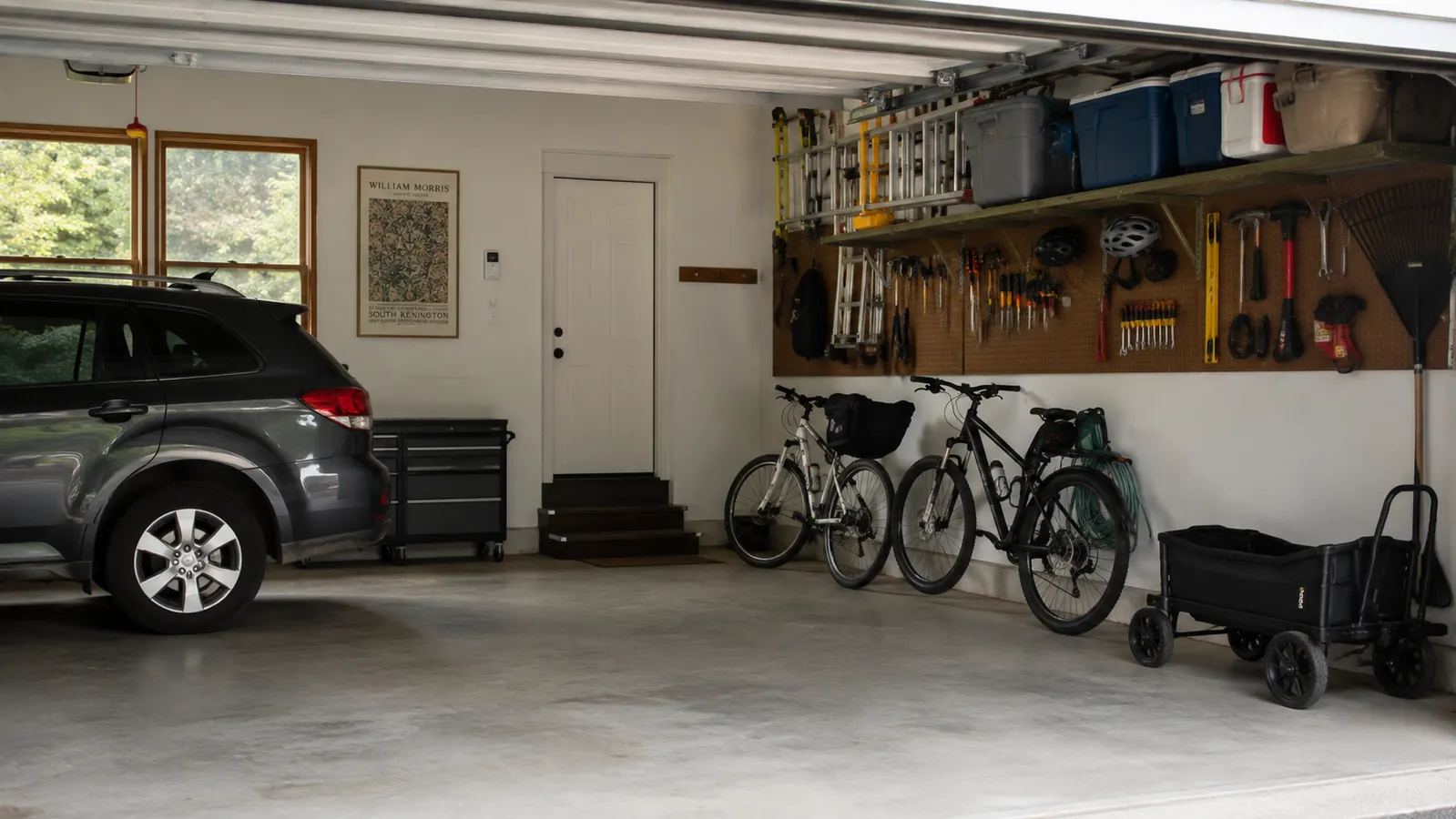 Garage with car parked inside and two bikes leaned against a wall, floor clear of loose tools and bins