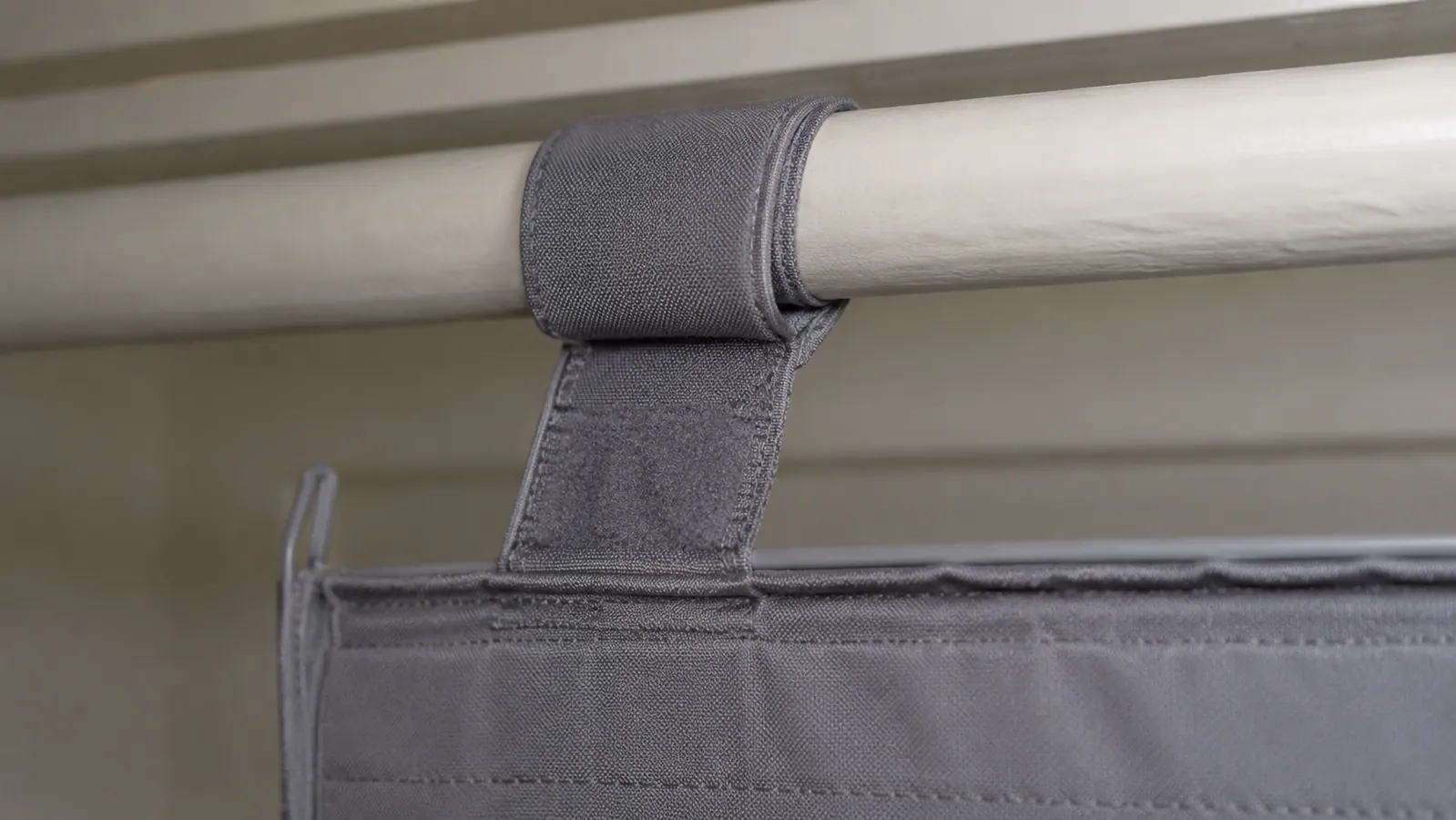 A close-up of the hanging strap and top of the closet organizer where it loops over a round closet rod, showing the hook-and-loop closure