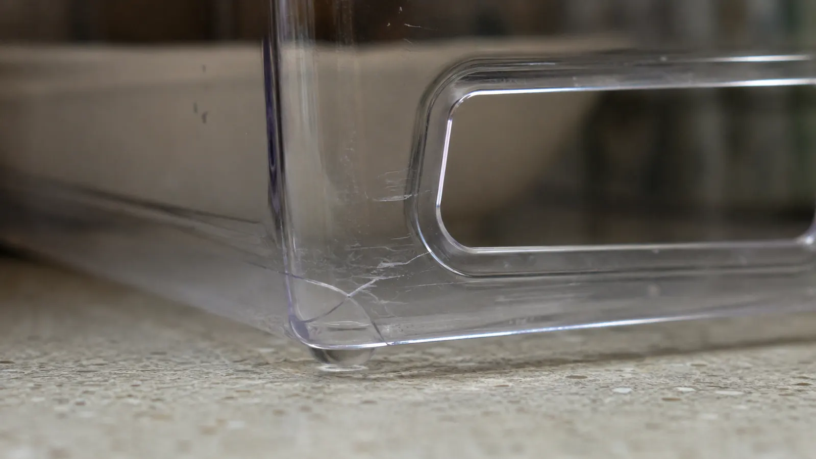 Close-up of scuff marks on the bottom corner of a clear plastic storage bin